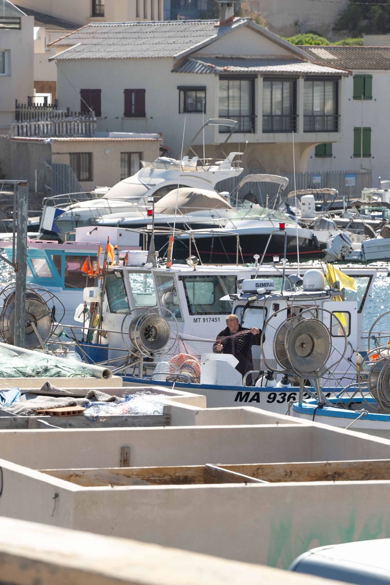 Un pêcheur remonte ses filets sur son bateau, dans le port des Goudes