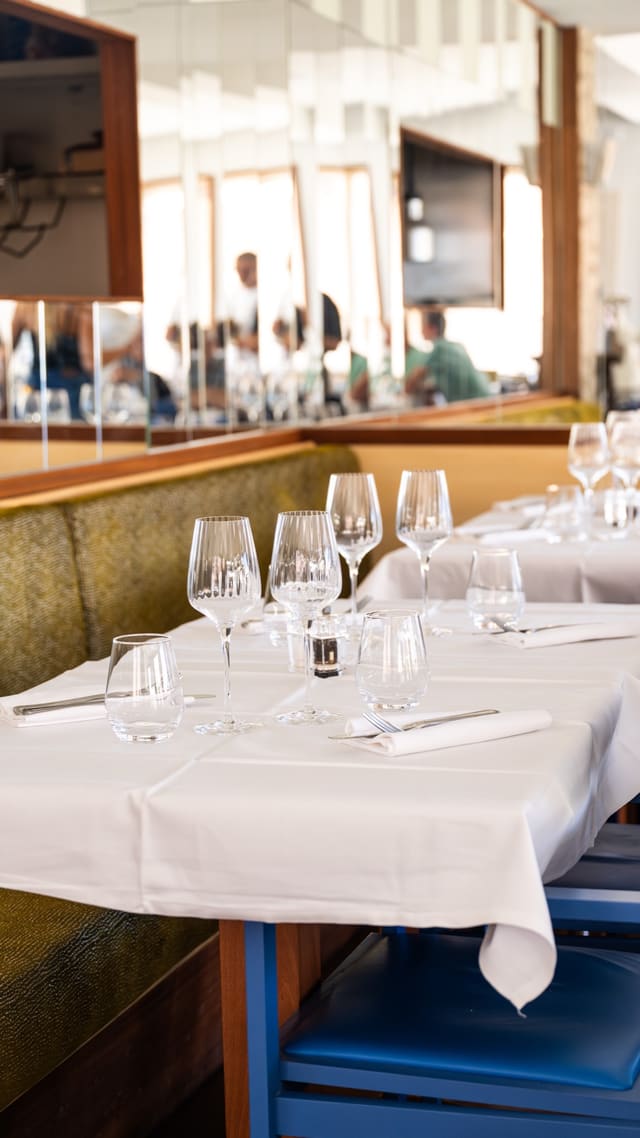 La salle de La Marine des Goudes : nappes blanches, banquettes et chaises bleues